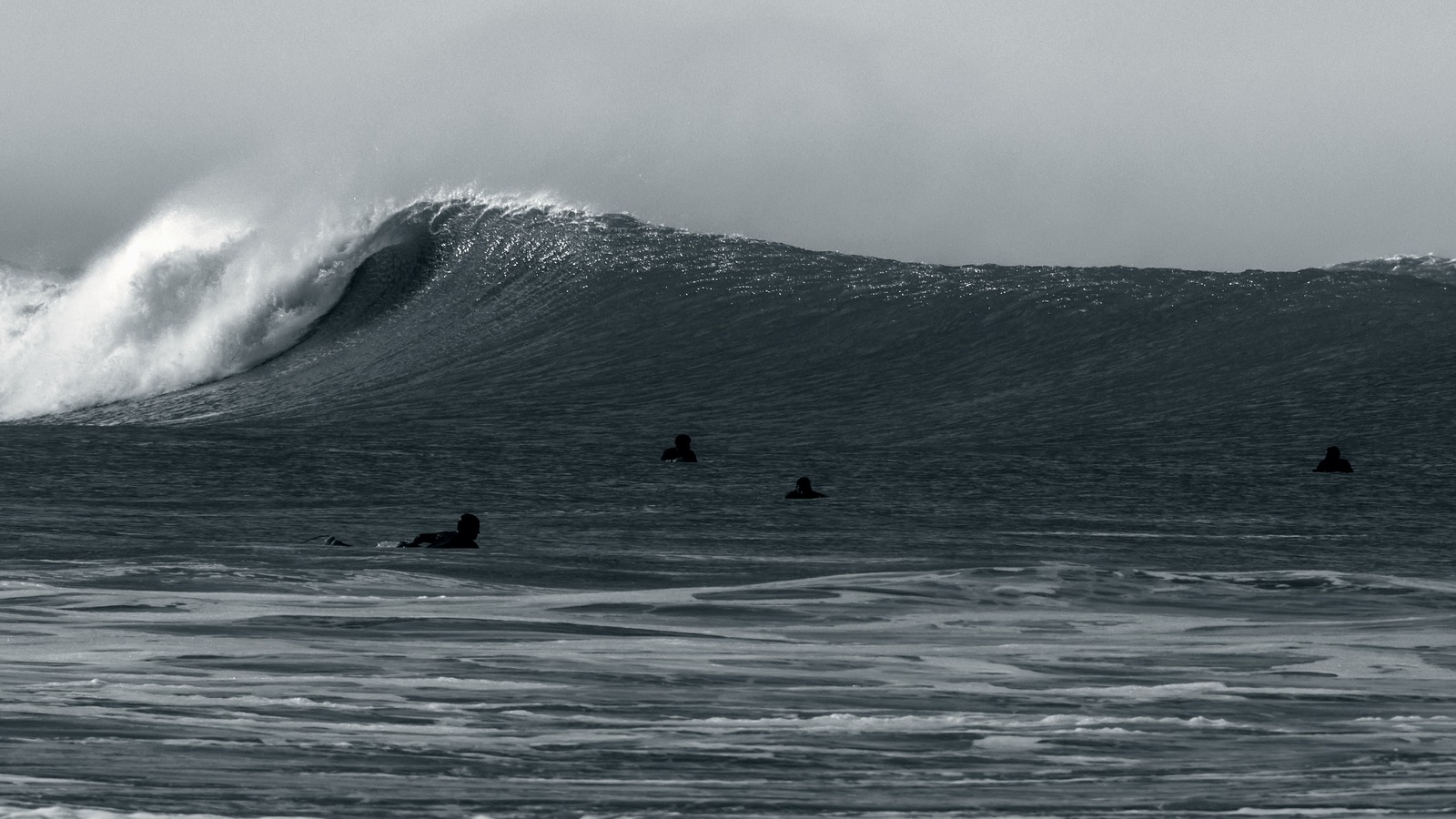 Quatre surfeurs qui attendent dans le lineup